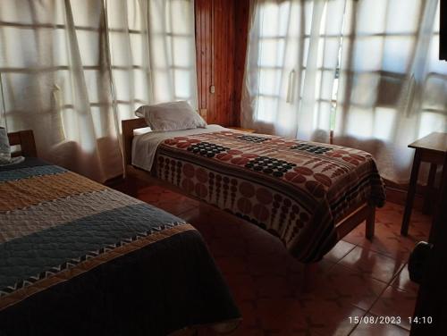 2 Betten in einem Zimmer mit Fenstern in der Unterkunft Hospedaje Aurora in Oxapampa