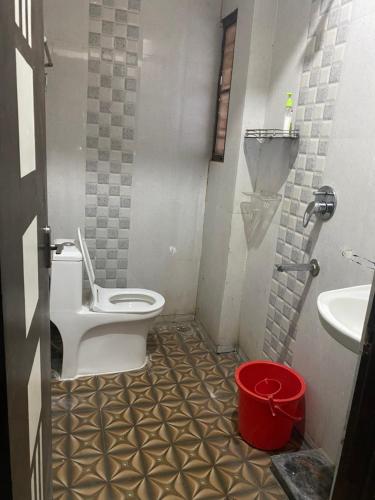 a bathroom with a toilet and a sink and a bucket at Ghar-fully furnished house with 2 Bedroom hall and kitchen in Bengaluru