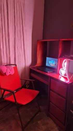 Habitación con silla roja y escritorio con ordenador portátil. en Casa Apreta2, en San Isidro