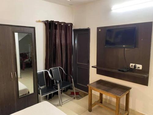 um quarto com duas cadeiras e uma televisão e uma mesa em Hotel royal orbit em Zirakpur