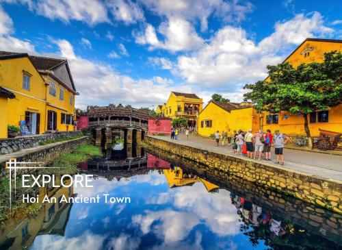 a group of people standing next to a canal with buildings at Hoi An Riverside Villas & Apartments in Hoi An
