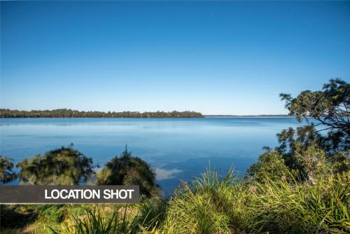a view of a lake with a sign that reads location shot at Paradise Beach House - Belle Escapes Jervis Bay in Sanctuary Point