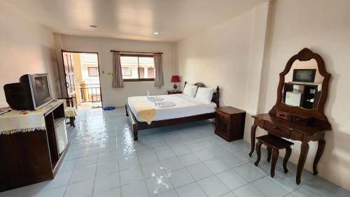 a bedroom with a bed and a tv and a mirror at Panupong Hotel in Chaweng