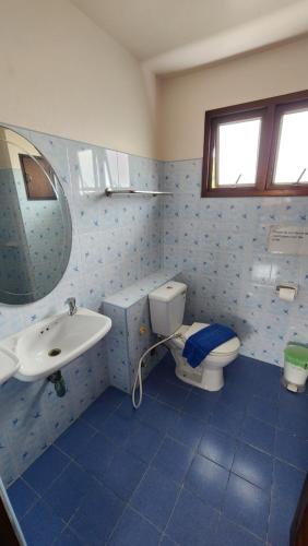a blue tiled bathroom with a toilet and a sink at Panupong Hotel in Chaweng