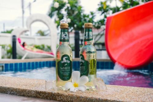 two bottles of beer sitting next to a swimming pool at so happy pool villa hua hin in Ban Bo Fai (1)