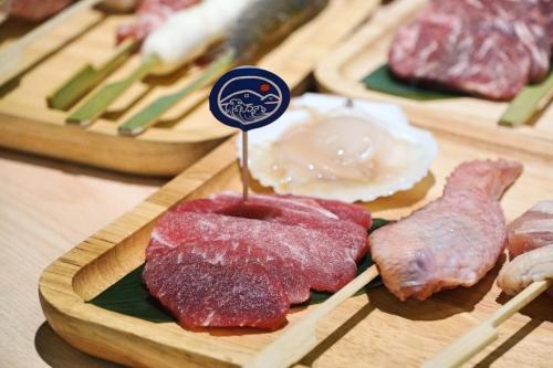 a bunch of different types of meat on wooden plates at Hibnb Guesthouse in Zhuangwei