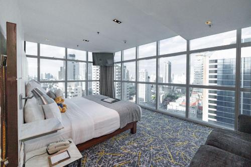 1 dormitorio con 1 cama grande y ventanas grandes en S31 Sukhumvit Hotel, en Bangkok