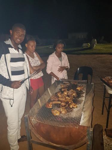 a group of people standing next to a grill at Okahatjipara Lodge 