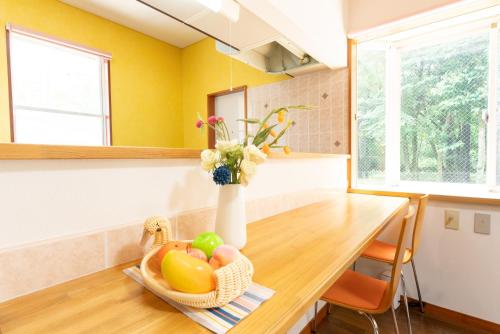 a kitchen with a table with a vase of flowers at Green Oasis Cottage Hakone Sengokuhara - グリーンオアシスコテージ箱根仙石原 in Sengokuhara