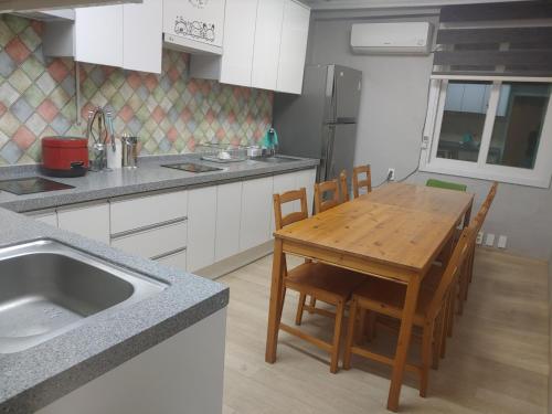 T stay guesthouse في تشونغجو: مطبخ مع طاولة خشبية مع كراسي ومغسلة