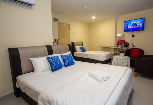 a hotel room with two beds and a flat screen tv at Southern Tip Hotel in Pontian Kecil