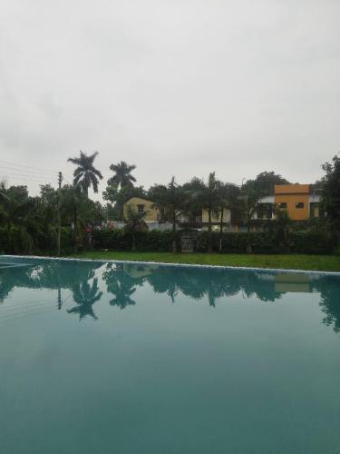 a view of a swimming pool with palm trees and houses at The HeartWood Farms Inn in Rāmnagar