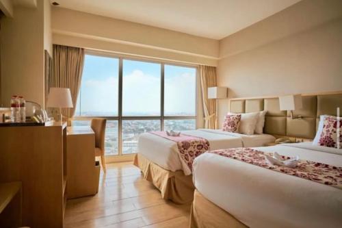 Cette chambre comprend 2 lits et une fenêtre. dans l'établissement Apart Kurnia house modern, à Semarang