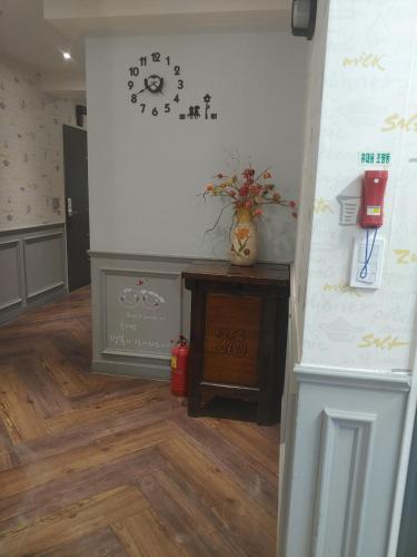 a room with a clock on the wall and a table at T stay pension in Cheongju