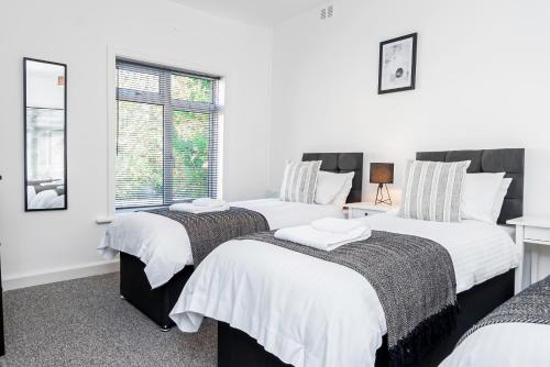 3 camas en una habitación con paredes blancas y ventana en City Centre 3 Bed 8 Guest Parking Near Mayflower, en Southampton