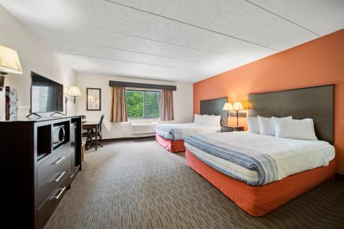 a hotel room with two beds and a desk at AmericInn by Wyndham Ames in Ames