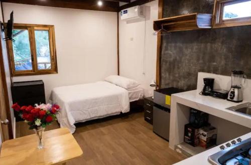 Cette petite chambre comprend un lit et une table fleurie. dans l'établissement Casa Happy Beach Ayampe, à Puerto López