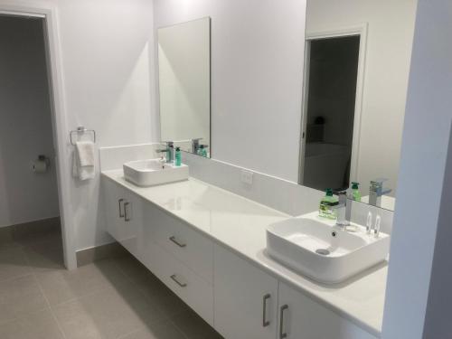 a white bathroom with two sinks and a mirror at Kincaid@230 in Wagga Wagga