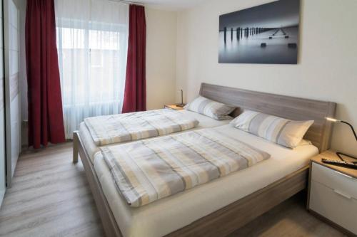 ノルトダイヒにあるFerienhaus Strandlustのベッドルーム1室(赤いカーテン付きの大型ベッド1台付)