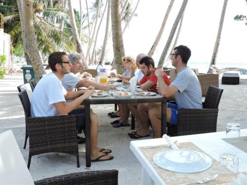 a group of people sitting at a table on the beach at Batuta Maldives Inn in Thulusdhoo