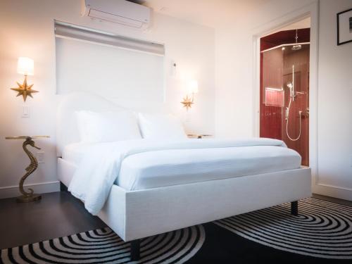 a white bedroom with a large white bed and a shower at The Redline Venice in Los Angeles