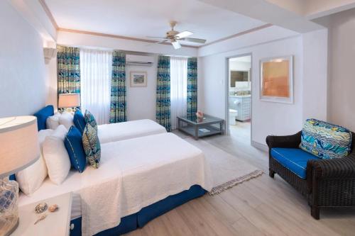 ein Schlafzimmer mit einem Bett und einem blauen Stuhl in der Unterkunft Westshore Beach House by Blue Sky Luxury in Saint James