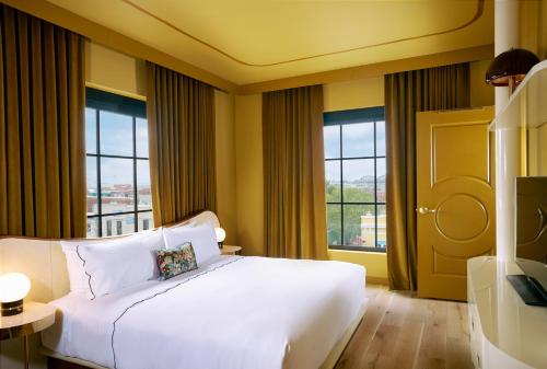 a bedroom with a large white bed and windows at Hotel Genevieve in Louisville