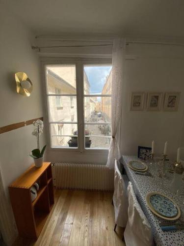 un salon avec une table et une fenêtre dans l'établissement Coeur de Versailles Notre Dame - 3 pièces, à Versailles