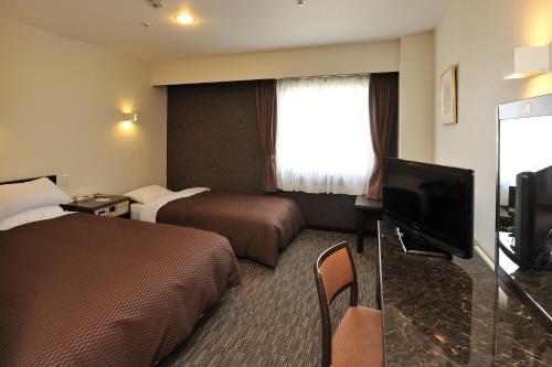 Habitación de hotel con 2 camas y TV de pantalla plana. en Matsuzaka Frex Hotel, en Matsusaka