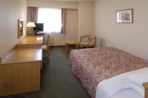 a hotel room with a bed and a desk at Matsuzaka Frex Hotel in Matsuzaka