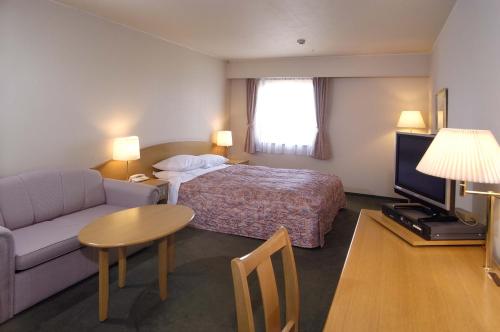 a hotel room with a bed and a couch and a table at Matsuzaka Frex Hotel in Matsuzaka