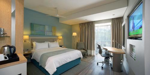 a hotel room with a bed and a flat screen tv at Holiday Inn Mauritius Mon Trésor by IHG in Blue Bay