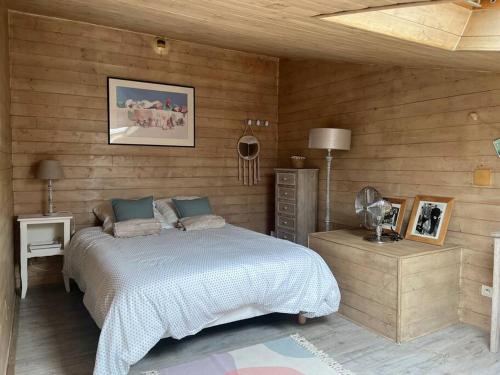 1 dormitorio con 1 cama y pared de madera en Cabane des Flamants YourHostHelper, en Gruissan