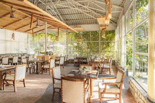 a restaurant with tables and chairs and windows at The Sylvan Retreat in Dehradun