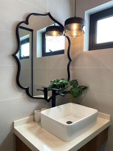 a bathroom with a white sink and a mirror at Arau House in Arau