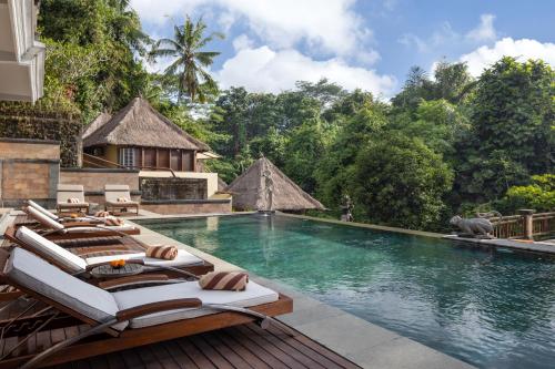 a pool at a resort with lounge chairs and a swimming pool at The Pari Sudha in Ubud