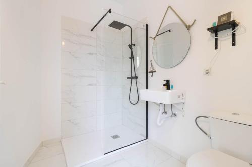 baño blanco con ducha y lavamanos en La Bussola, en Las Palmas de Gran Canaria