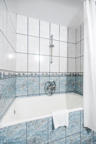 a bath tub in a bathroom with blue tiles at Hotel Imparatul Romanilor Hotel & SPA in Sibiu