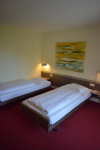 two beds in a room with a painting on the wall at Schloss Reinach in Freiburg im Breisgau
