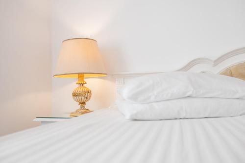 a bed with white sheets and a lamp on a table at Hotel Imparatul Romanilor Hotel & SPA in Sibiu