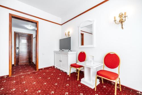 a room with two chairs and a table and a tv at Hotel Imparatul Romanilor Hotel & SPA in Sibiu
