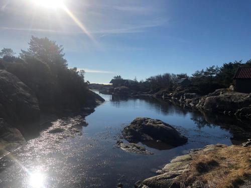 a river with rocks and the sun in the sky at Brightside Apartment in Kristiansand