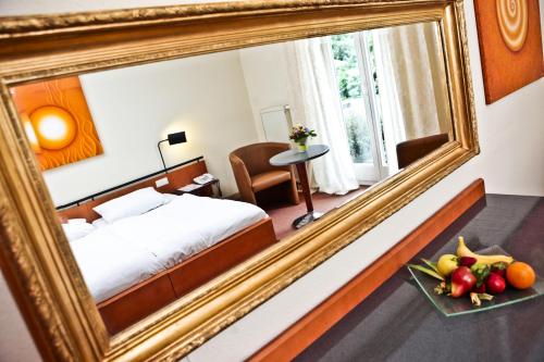 a mirror in a hotel room with a bed and a plate of fruit at Schloss Reinach in Freiburg im Breisgau