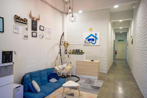 a living room with a blue couch and a white wall at Buddy Station in Semporna