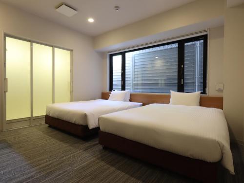 a hotel room with two beds and a window at Hotel Glad One Kyoto Shichijo by M's in Kyoto