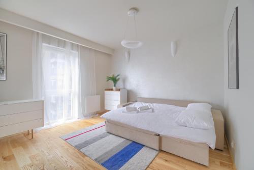 a white bedroom with a bed and a window at Gąsiorowskich Beige Apartment in Poznań