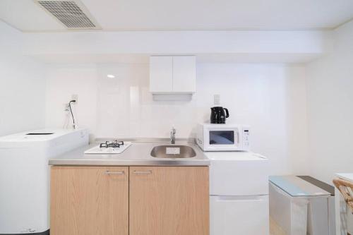 a white kitchen with a sink and a microwave at Takadanobaba Address102 in Tokyo