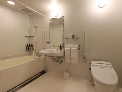Baño blanco con aseo y lavamanos en Hotel Glad One Kyoto Shichijo by M's en Kioto