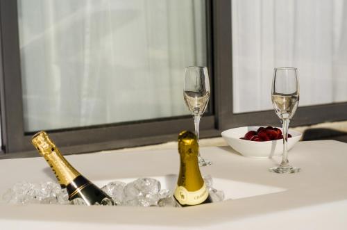 two champagne glasses and a bowl of fruit on a table at Paramount Bay Penthouse in Birżebbuġa