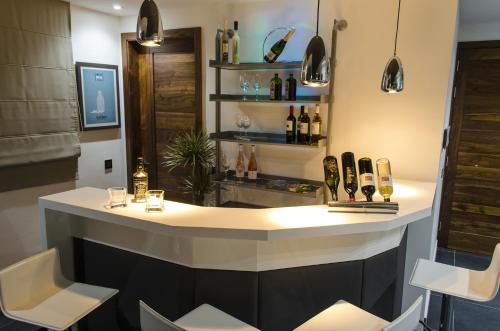 un bar con sillas blancas y botellas de vino en Paramount Bay Penthouse, en Birżebbuġa